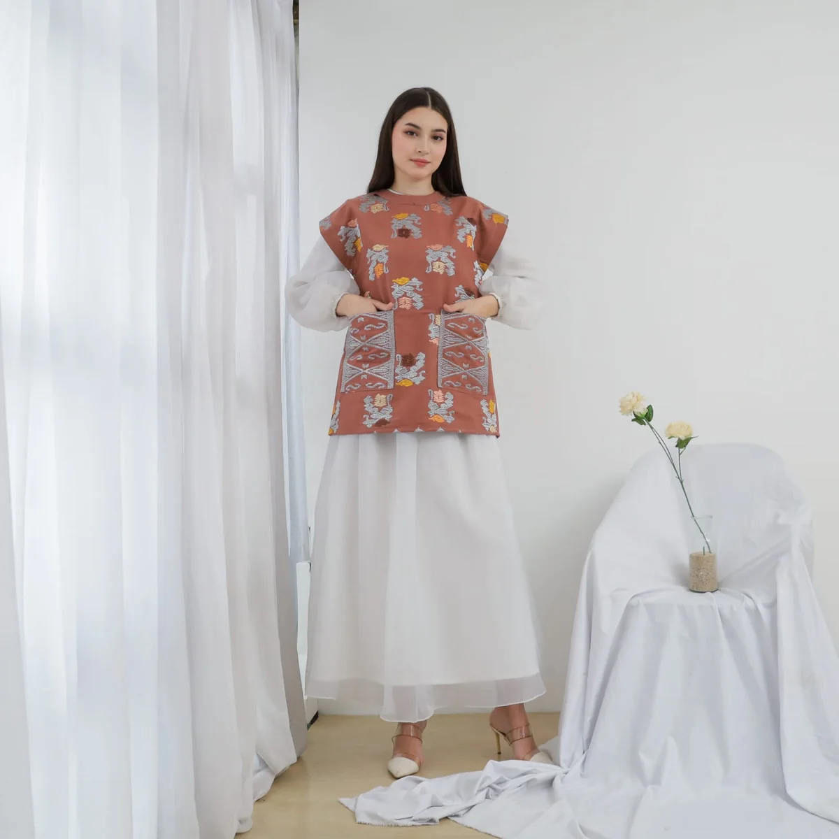 Model mengenakan Blouse Cempaka tenun Bali terracotta dengan bordir